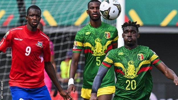 Mali midfielder Yves Bissouma (right) controls the ball next to Gambia forward Assan Ceesay