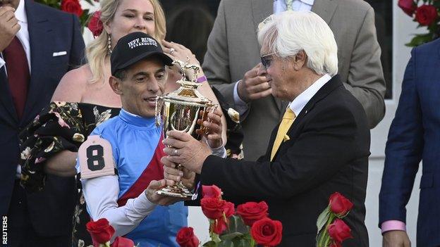 Jockey John Velazquez (left) and trainer Bob Baffert (right) hold up the trophy after Medina Spirit won the 2021 Kentucky Derby