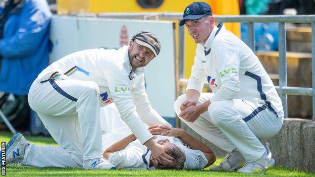 Adam Lyth and George Hill help Dominic Leech after his injury in the outfield