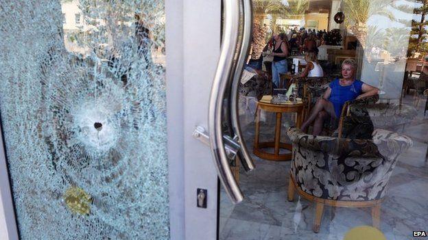 A tourist at the Imperial Marhaba Hotel sits near a door shattered by a bullet