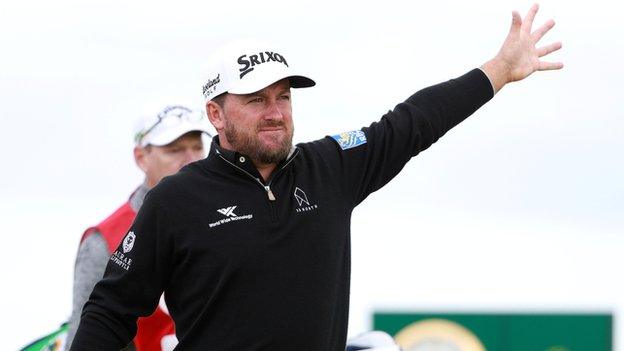 Graeme McDowell alerts spectators of an errant drive during a frustrating opening round