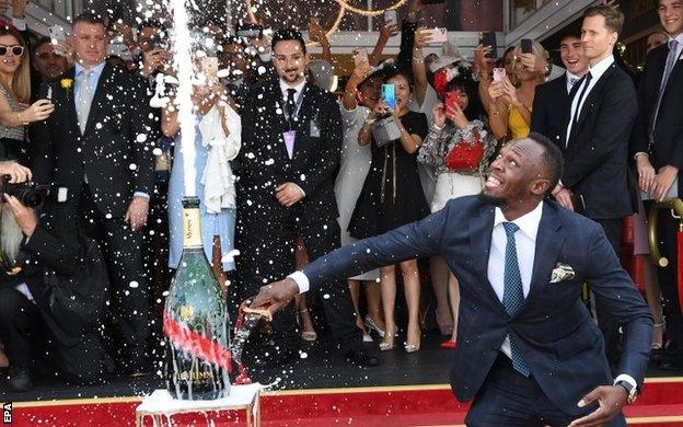 Usain Boltn opens a bottle of champagne at the Melbourne Cup