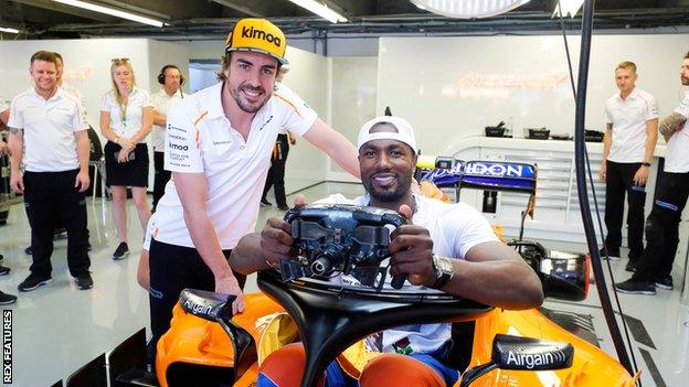 Spaniard Serge Ibaka Congolause of the NBA's Toronto Raptors tries the seat in the car of Fernando Alonso