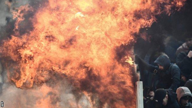 A firebomb lands just short of the Ajax section