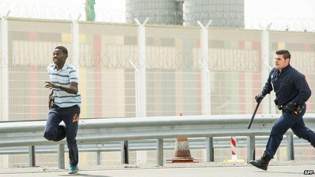 A French policeman chases a migrant near Calais port