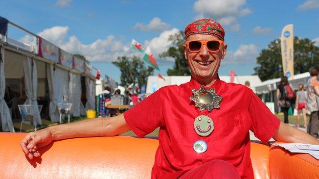 Mae'r artist Andrew Logan o Aberriw yn arddangos ei waith ar faes y Brifwyl // The artist Andrew Logan from Berriew enjoying the sun on a red-hot day