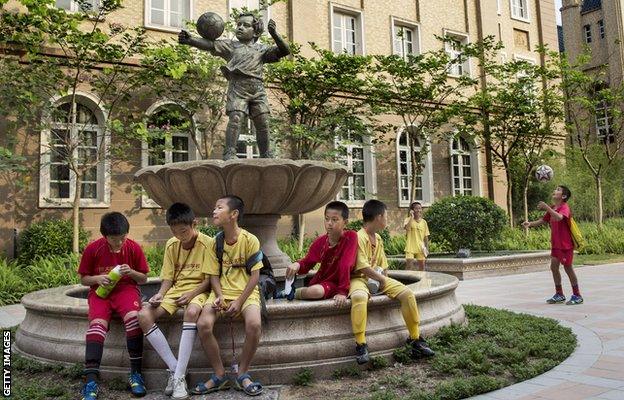 Young Chinese football players sit together in the campus as they wait to head to training at the Evergrande International Football School