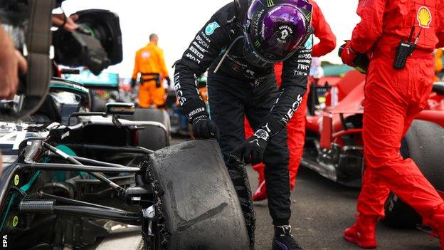 Lewis Hamilton checks his punctured tyre at the end of the British Grand Prix