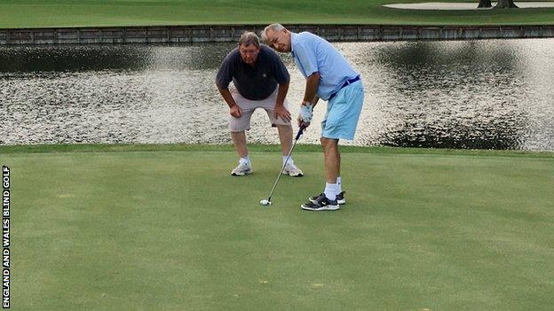 John Eakin putting on the 17th green at Sawgrass in a practice round with his guide Steve Killick lining up the shot