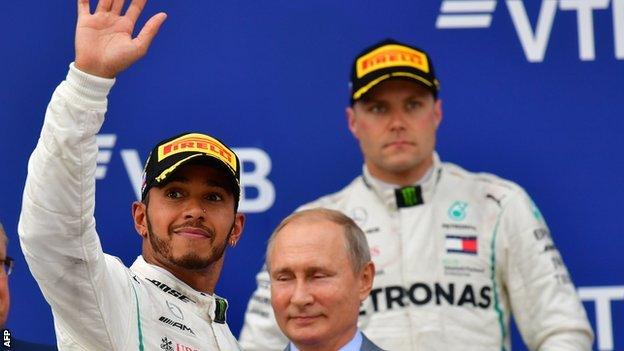 Lewis Hamilton waves on the podium after the Russian GP, with Valtteri Bottas and Russia president Vladimir Putin watching on