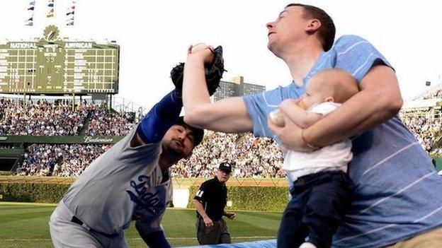 Father catches ball at Major League Baseball game with son in hand