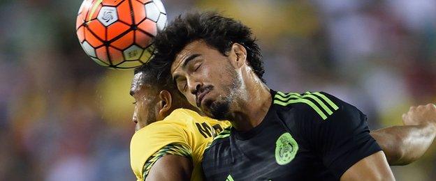 Mexico"s Oswaldo Alanis goes for the ball against Jamaica"s Adrian Mariappa