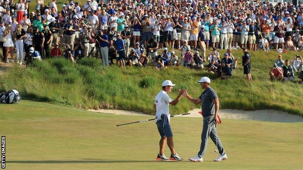 Brooks Koepka celebrates with caddy Ricky Elliott on the 18th green at Shinnecock Hills