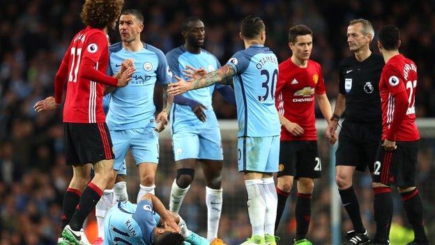 Marouane Fellaini gestures with his palms facing outwards as he stands over the fallen Sergio Aguero