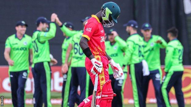 A dejected Tadiwanashe Marumani walks off as Ireland celebrate taking his wicket in the second T20