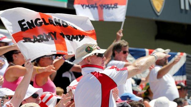 A member of England's Barmy Army signals a four