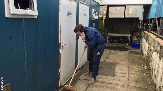 Southport boss Kevin Davies sweeps up broken glass after a break-in at the club's training ground