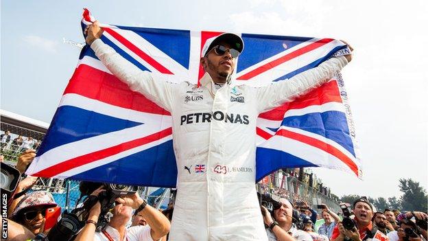 Lewis Hamilton holding a Union Jack flag after winning the drivers' title in Mexico in 2017