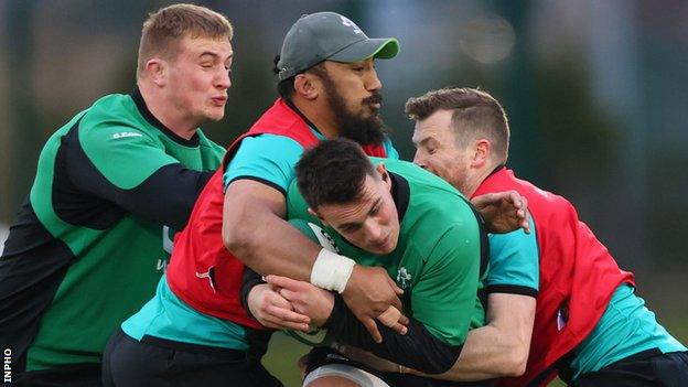 Bundee Aki and Jack Carty try and hold up James Hume in Ireland training on Thursday