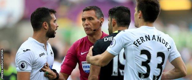 Referee Andre Marriner with Swansea defenders Jordi Amat (l) and Federico Fernandez (r) and Chelsea striker Diego Costa