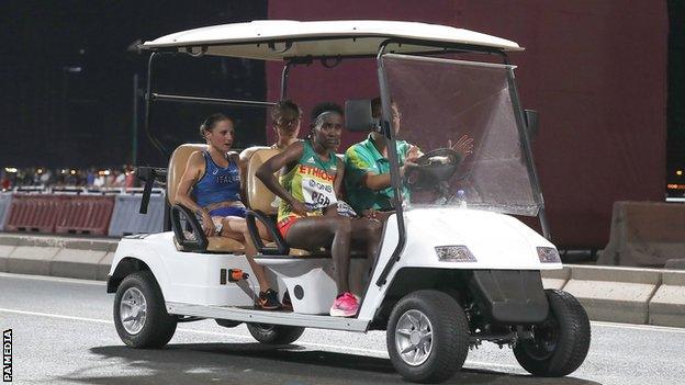 Four athletes are driven to the finish area in a kart after pulling out of the women's marathon