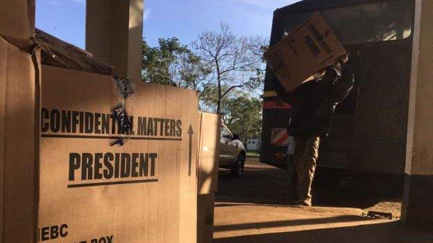 A sealed ballot box is stacked amongst others