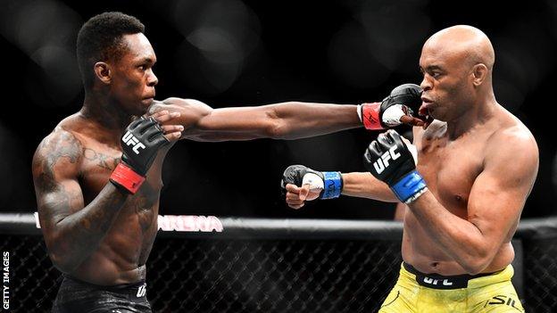 Israel Adesanya (left) aims a blow at Anderson Silva