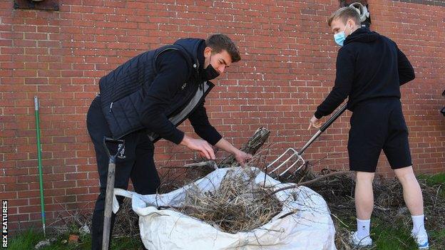 Lincoln City's Alex Palmer and Anthony Scully pitch in to help members of the Sincil Community Land Trust regenerate a garden