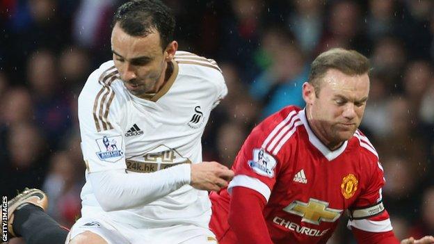 Leon Britton is challenged by Wayne Rooney