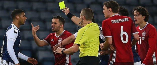 Scotland midfielder Liam Bridcutt (left) is booked for his challenge