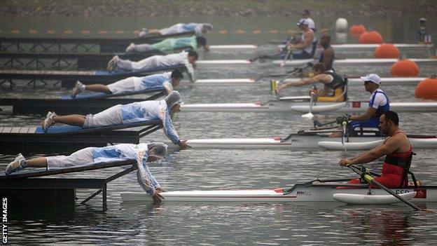 Volunteers hold boats ahead of the men's sculls race, Beijing Paralympics 2008