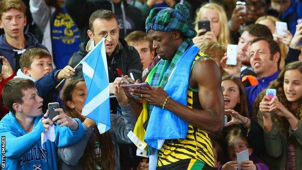 Usain Bolt of Jamaica signs autographs after winning gold in the 4x100m relay at Glasgow 2014