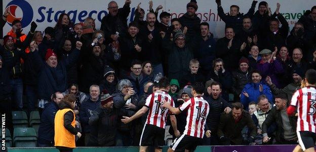 Lee Frecklington (centre, number 19) celebrates his goal for Lincoln with the home support at Sincil Bank