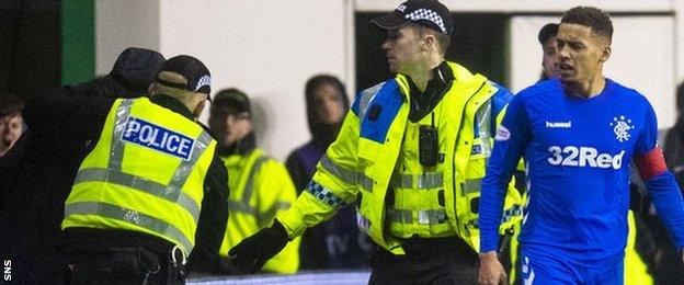 A fan is led away by police after confronting Rangers' James Tavernier