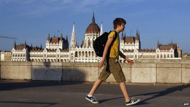 A teenage boy walking in front the Hungarian parliament