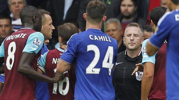 West Ham and Chelsea players surround referee Jon Moss during a game between their sides in October