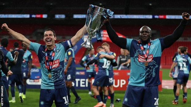 Matt Bloomfield (left) pictured alongside Adebayo Akinfenwa after winning promotion to the Championship with Wycombe in 2020 - his fourth promotion with the club