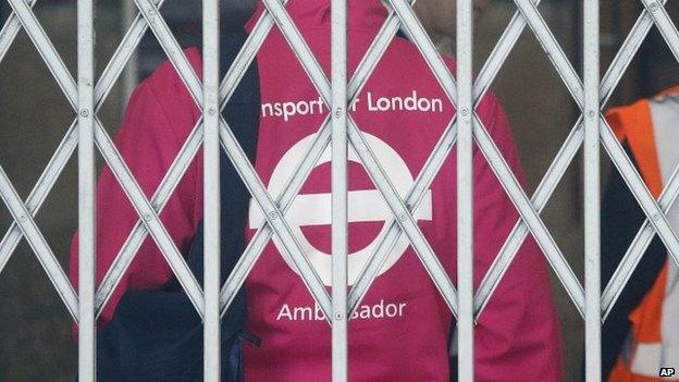 A transport assistant waits behind the fence of the closed tube station at Victoria as tube drivers are on strike in London