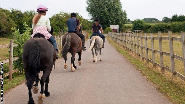 Three ponies being ridden into the distance