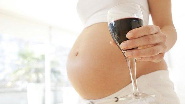 A pregnant woman holding a glass of wine