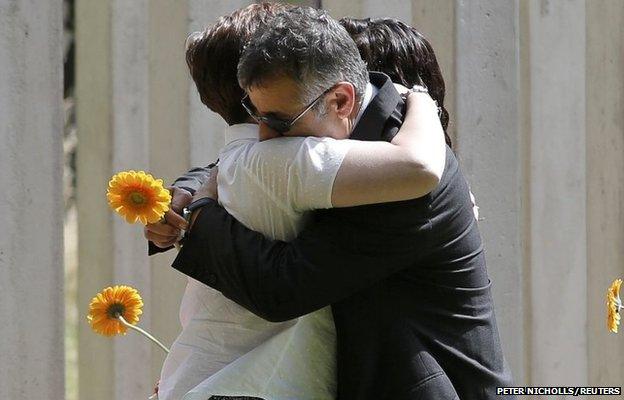 Mourners embrace as they attend a memorial event