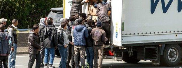 Migrants climb in the back of a lorry in Calais