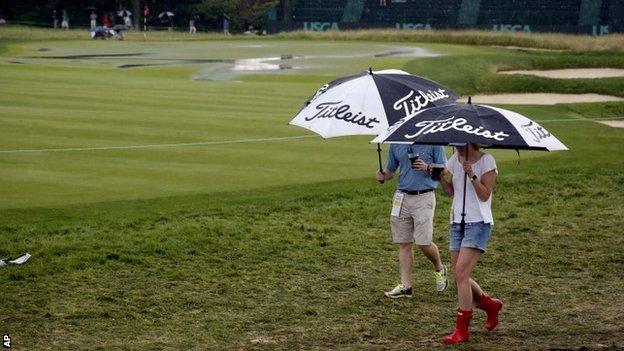 Fans on the Oakmont course shelter from the rain