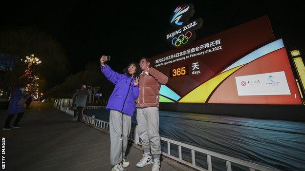 People take a picture by the Beijing 2022 sign