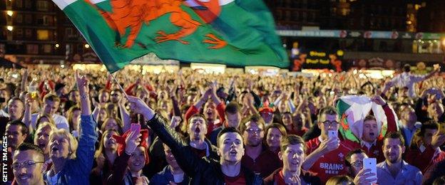 Supporters waving Wales flags celebrate in one of the World Cup fan zones