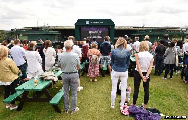 Spectators on Murray Mound (Henman Hill) stand to observe a minute's silence