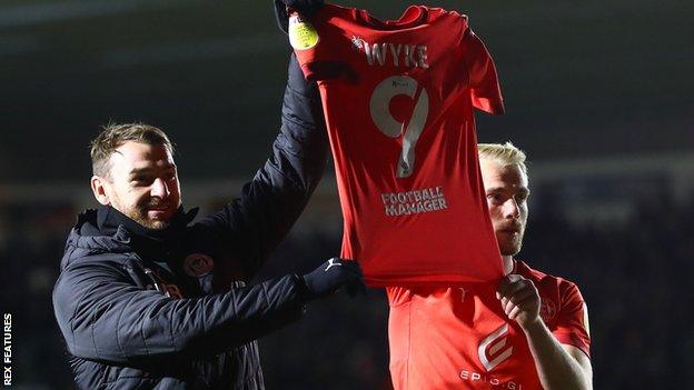 Wigan's players hold up Charlie Wyke's shirt after their late win at Plymouth Argyle