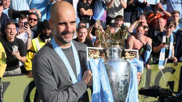 Manchester City boss Pep Guardiola poses with the Premier League trophy after winning the title