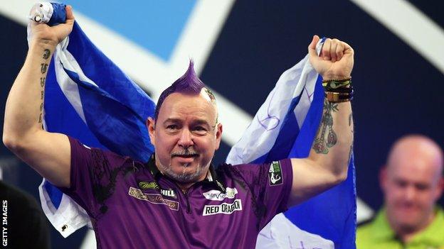 Peter Wright (left) holds up the Scotland flag as he celebrates beating Michael van Gerwen (right) to win the 2020 PDC World Darts Championship