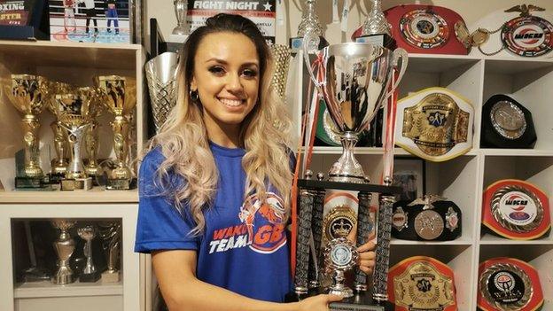 Tennessee Randall holding her World Champion trophy in front of an impressive collection of silverware